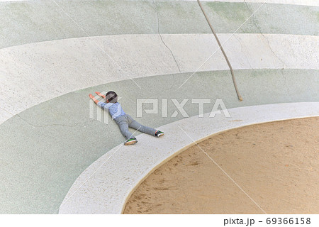 ロープを使って上まで登る、すり鉢状の公園の遊具を登れず諦めてしまった子供の姿 69366158
