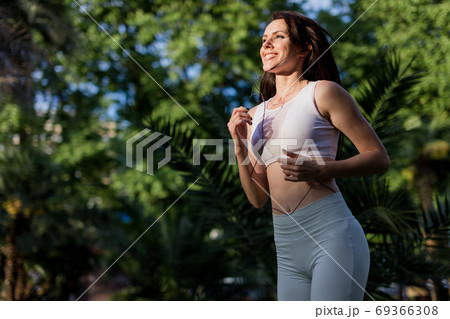 Young woman doing Yoga outdoors in park in white sportswear. Active vacation. 69366308