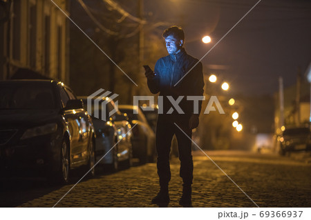 The man phone on the street. Evening night time. Telephoto lens shot 69366937