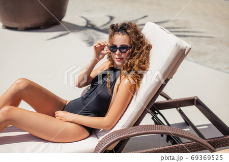 Young beautiful sexy brunette in swimsuit sitting near the pool 69369525