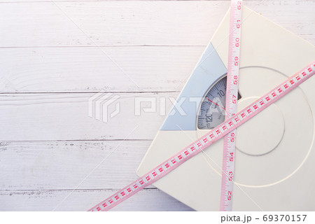 a tape measure and Bathroom scale on wooden floor. a tape measure and Bathroom scale on wooden floor. 69370157