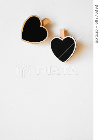 Two heart wooden black chalkboard clothespin on white wall, vert 69370393