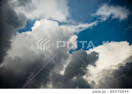 CLOSE UP: Dark grey stormy clouds gather above Lake Maggiore on a calm summer evening. Dramatic shot of clouds covering up the colorful sunlit morning sky. Orange hued evening sky and stormy clouds. 69370844