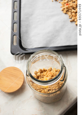 Muesli in glass jar on parchment paper on baking sheet, above. M 69371449