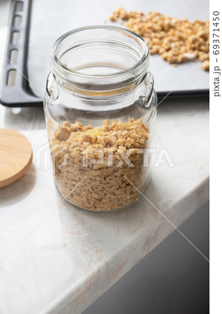 Close-up muesli in glass jar on parchment paper on baking sheet, 69371450
