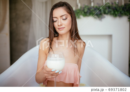 Sensual attractive woman relaxing in bath with glass of milk. Sensual attractive woman relaxing in bath with glass of milk. 69371802