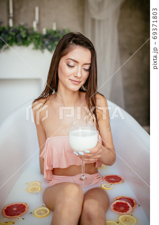 Sensual attractive woman relaxing in bath with glass of milk. Sensual attractive woman relaxing in bath with glass of milk. 69371803