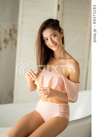 An Attractive girl relaxing in bath on light background An Attractive girl relaxing in bath on light background 69373283