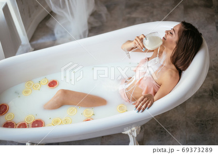 Sensual attractive woman relaxing in bath with glass of milk. Sensual attractive woman relaxing in bath with glass of milk. 69373289