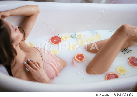 A young brunette woman takes a milk bath. 69373330