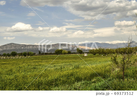 Valley with apricot orchards, vineyards on the background of the spring evening sky and the mountains of Geghama ridge in Armenia 69373512