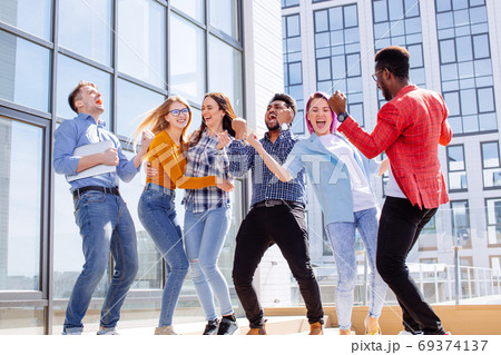 Group of multi ethnic youngsters chilling in urban outdoor background Group of multi ethnic youngsters chilling in urban outdoor background 69374137
