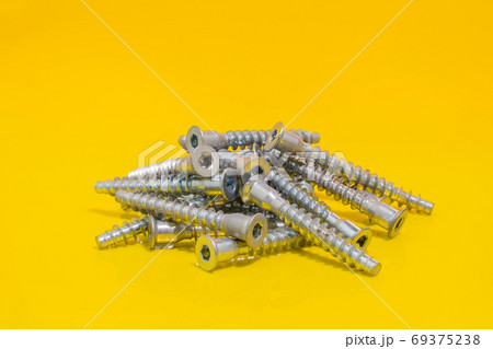 Screw bolts for furniture assembling on yellow background. 69375238
