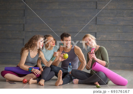 Young man and women resting on floor after successful exercising in gym. 69376167