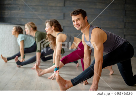 Yoga beginners exercising against grey wall, doing yoga or pilates posture. Yoga beginners exercising against grey wall, doing yoga or pilates posture. 69376326