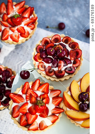Fresh delicious cherry, strawberry and peach tartlets on gray ba 69376589