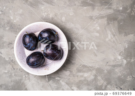 Fresh ripe plum fruits with water drops in wooden bowl Fresh ripe plum fruits with water drops in wooden bowl 69376649