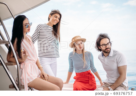 Travel, seatrip, friendship and people concept - friends sitting on yacht deck 69376757