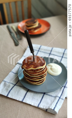 Plate with stack of homemade pancakes and sour cream on wooden table, selective focus Plate with stack of homemade pancakes and sour cream on wooden table, selective focus 69377570