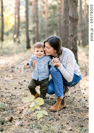 Young family, happy woman mom having fun in autumn pine forest with her child little son. Mother hugging her kid son during walk in the park Young family, happy woman mom having fun in autumn pine forest with her child little son. Mother hugging her kid son during walk in the park 69378009
