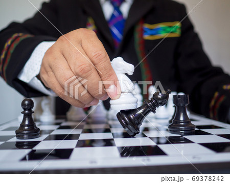 Businessman hand moving chess piece on board with white background Businessman hand moving chess piece on board with white background 69378242