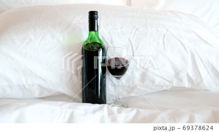 A glass of wine and wine bottle in the bed A glass of wine and wine bottle in the bed 69378624