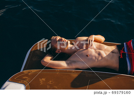 Young caucasian hipster guy enjoying journey on yacht deck sailing the sea. 69379160