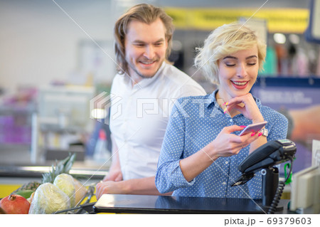 Woman at the supermarket checkout, she is paying using a credit card Woman at the supermarket checkout, she is paying using a credit card 69379603