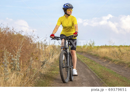 Beautiful girl in yellow riding a bike in nature. Sports and rec Beautiful girl in yellow riding a bike in nature. Sports and rec 69379651