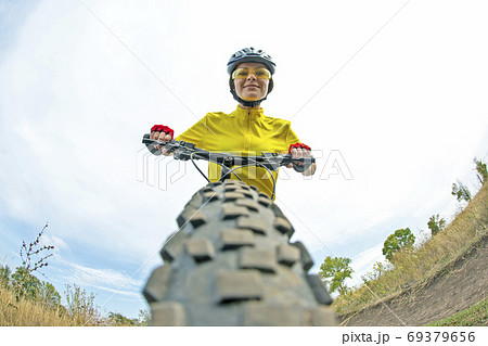 Beautiful girl in yellow riding a bike on the path in the field. Beautiful girl in yellow riding a bike on the path in the field. 69379656