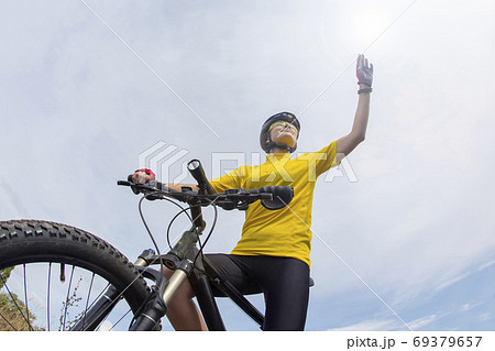 Beautiful girl cyclist with a bicycle on a sky background. Healt 69379657