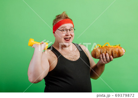 joyful fat male haqving fun with burger and dumbbell 69379872
