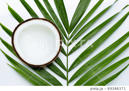 Half coconut on tropical palm leaves on white background. 69386371