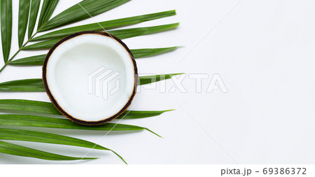 Half coconut on tropical palm leaves on white background. Half coconut on tropical palm leaves on white background. 69386372