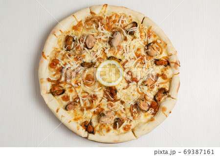 Italian pizza with seafood, mussels and calamari rings, decorated with lemon slice 69387161