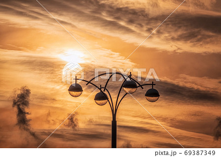 Street lamp on the background of the sunset sky with the silhouette of the sun Street lamp on the background of the sunset sky with the silhouette of the sun 69387349