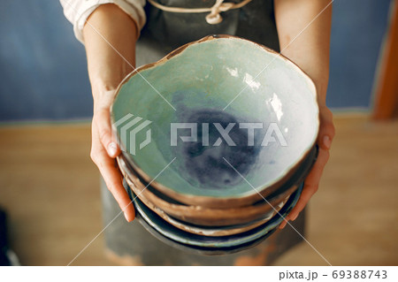 A young woman holds a ceramics dish in her hands A young woman holds a ceramics dish in her hands 69388743