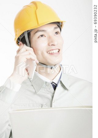 スマートフォンで通話する男性作業員 スマートフォンで通話する男性作業員 69390232