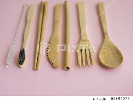 Eco friendly bamboo cutlery set in a case on a pink background. Zero waste concept. Set of bamboo cutlery in a case on a laying on a table. Spoon, fork, knife, toothbrush, tube and chinese sticks. 69394077