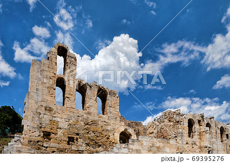 View of Odeon of Herodes Atticus theater on Acropolis hill, Athens, Greece, against bright blue sky and super clouds. UNESCO world heritage 69395276