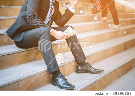 Man's hand is planning savings money to buy a home concept.Businessman keep dollar money in hand and think about the future house..Sad fired businessman sitting on the floor after failure and layoff. 69396888