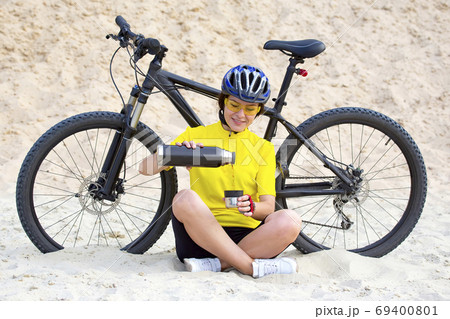 girl cyclist pours tea from a thermos on the background of a Bic 69400801