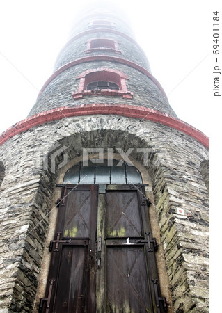 A lookout tower in the clouds. The stone tower is surrounded by a white mist. A lookout tower in the clouds. The stone tower is surrounded by a white mist. 69401184