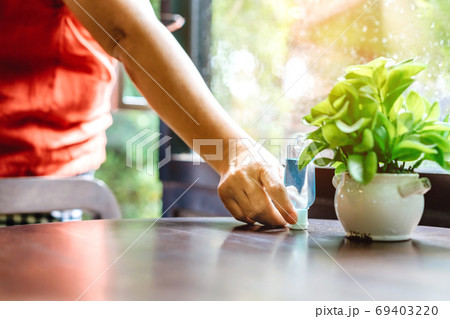 Hand of woman pick up blue alcohol gel bottle to prevent the spreading of the Coronavirus (Covid-19) before entrance to coffee shop. Healthcare concept. New normal lifestyle. Selective focus 69403220