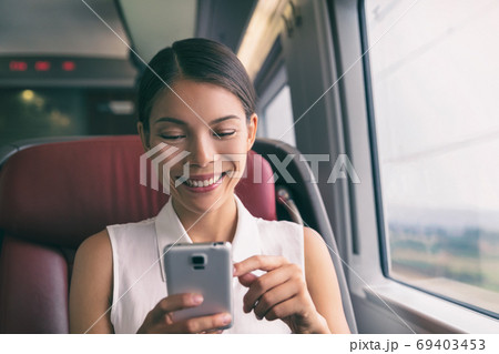 Train travel mobile phone Asian business woman using cellphone texting during commute to work. Commuting people lifestyle on transport with 5g device 69403453