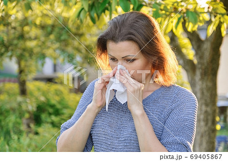 Seasonal allergies, woman with nasal wipe, sneezing, wiping nose outdoor Seasonal allergies, woman with nasal wipe, sneezing, wiping nose outdoor 69405867