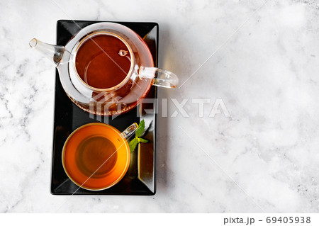 Top view of glass tea cup and glass kettle on black tray and white backround Top view of glass tea cup and glass kettle on black tray and white backround 69405938