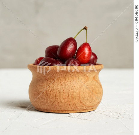 ripe red dogwood berries in a wooden bowl, gray background ripe red dogwood berries in a wooden bowl, gray background 69406690