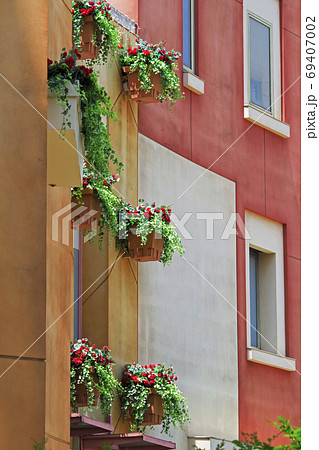 窓に赤い花の観葉植物が飾られた南欧風の建物の外観の写真素材