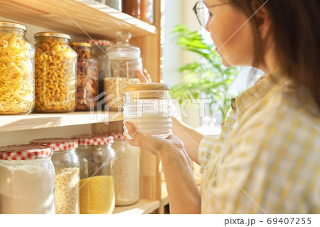 Food storage in pantry, woman holding jar of sugar in hand. Food storage in pantry, woman holding jar of sugar in hand. 69407255